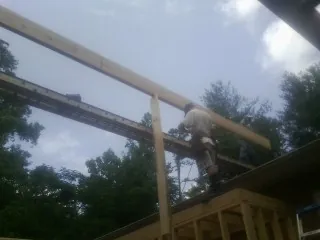 Carpenter setting a ridge beam over a new addition frame — Ice Dam Removal by Roofing Brothers in Clarksburg