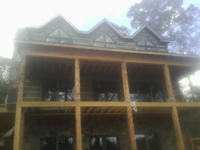 Dormers and porch framing on a large log home under construction — Roof Coating work by our crew in Clarksburg