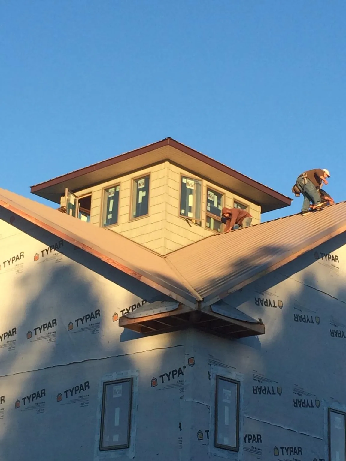 Roofers working around a rooftop cupola on a new metal roof at sunset — Roof Waterproofing in Clarksburg by Roofing Brothers